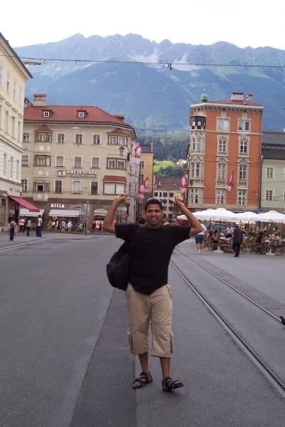 Gagan posing in a town square with mountains behind him