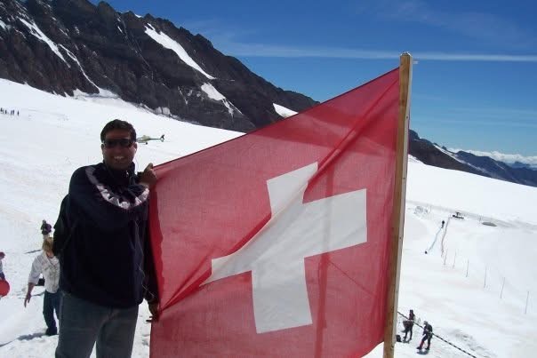 Gagan holding a large Swiss flag on a snowfield