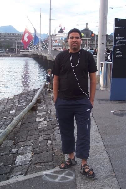 Gagan standing beside a waterfront with Swiss flags