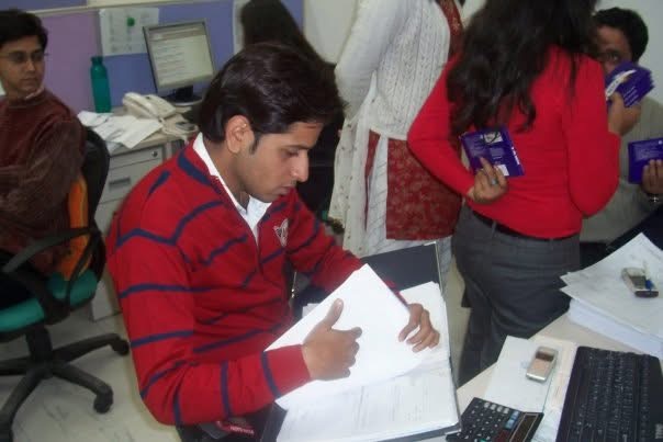 Gagan’s friend in a red striped sweater, seated at a desk