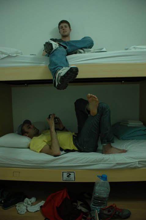 Two roommates relaxing on bunk beds in a hostel