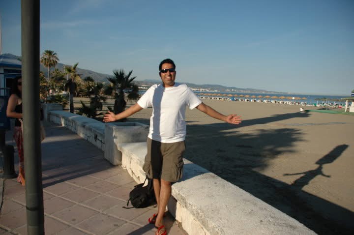 Gagan with open arms beside a Spanish beach