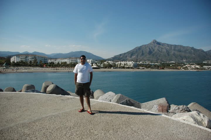Gagan on a Spanish waterfront with mountains beyond the bay