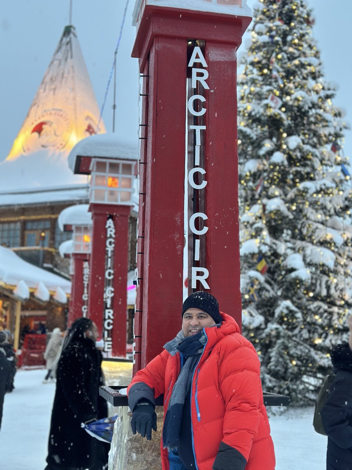 Gagan by a Christmas tree and Arctic Circle marker