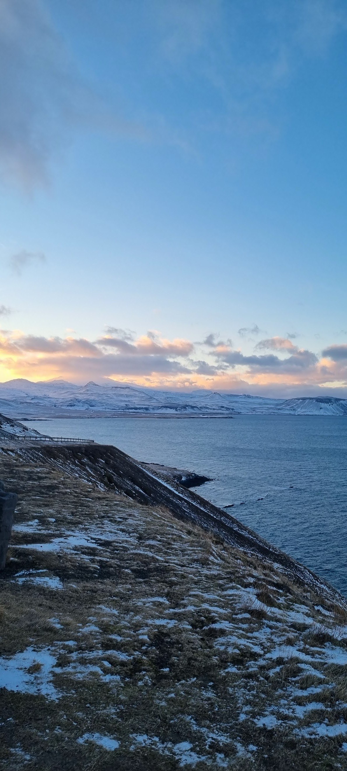 Water and snowy hills under a pastel sky