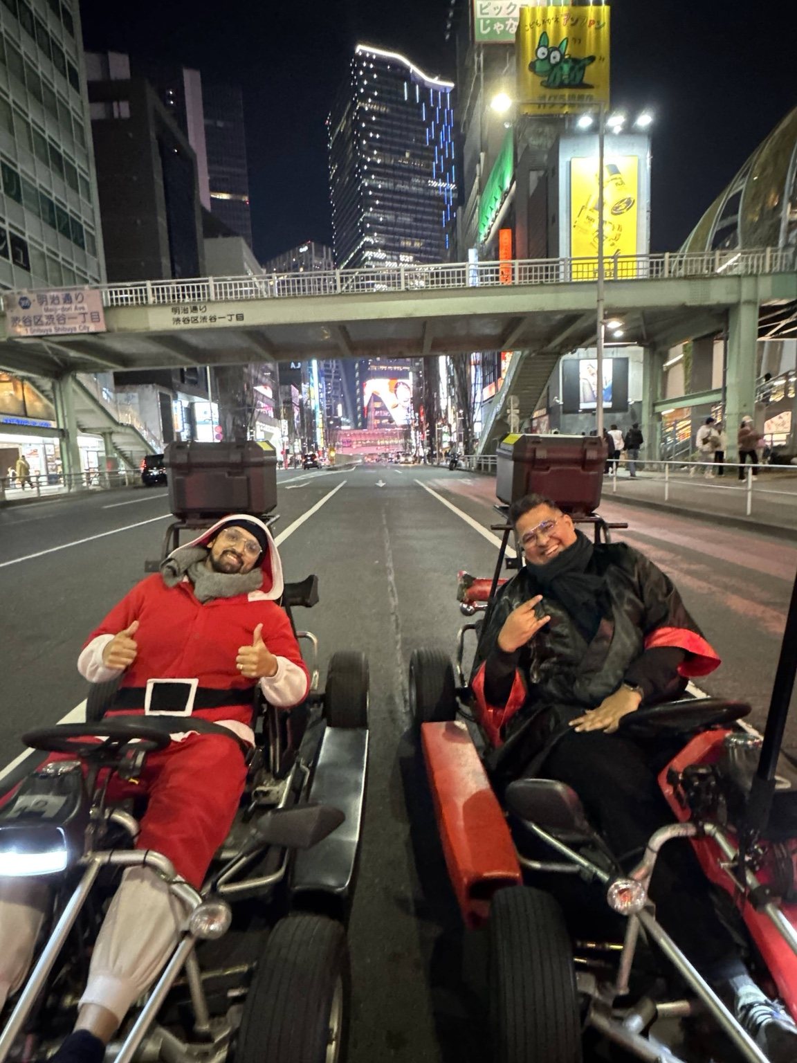Two travelers in go karts on a city street at night