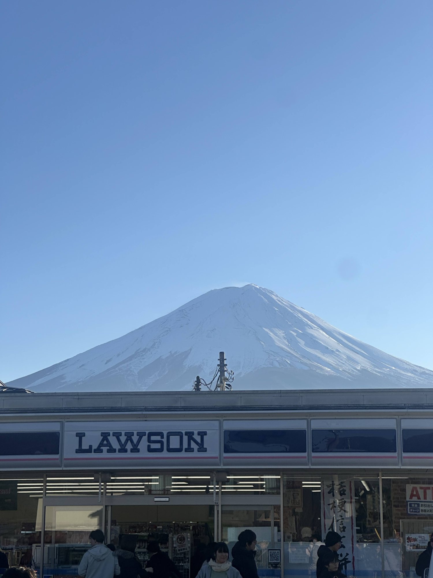 Snow-covered Mount Fuji above a convenience store
