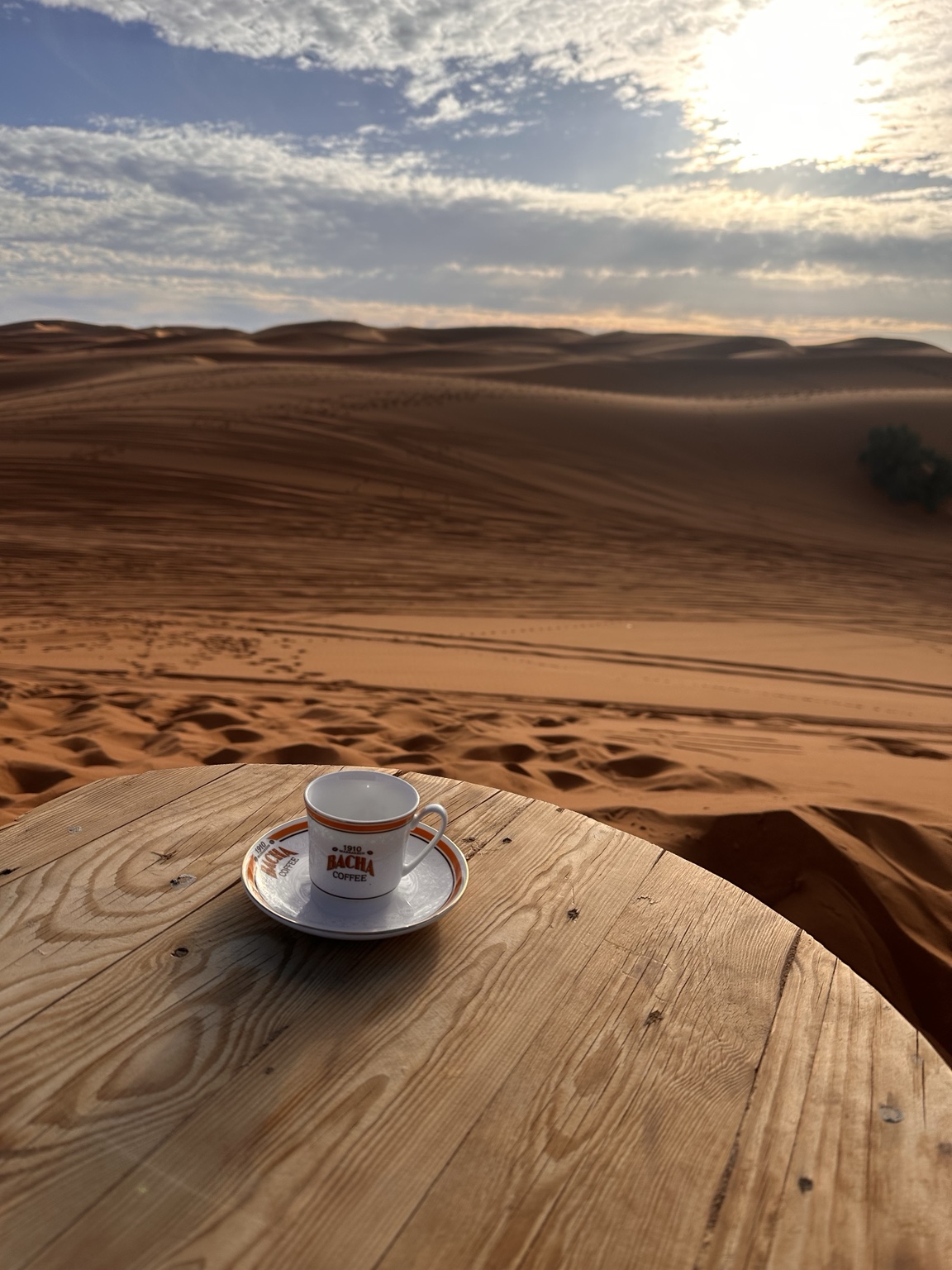 A coffee cup on a table overlooking the Sahara dunes