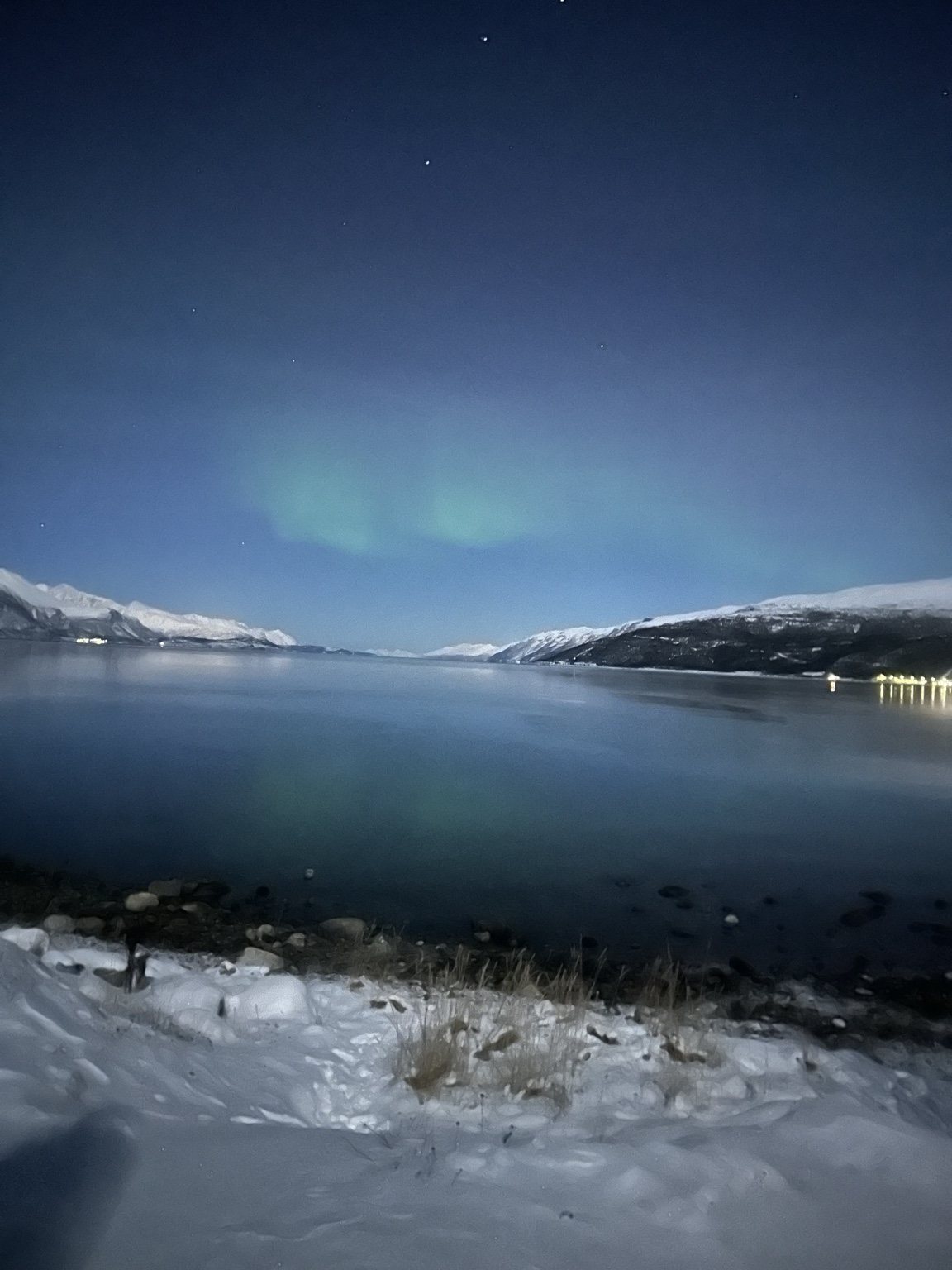 Dark fjord beneath a faint green glow