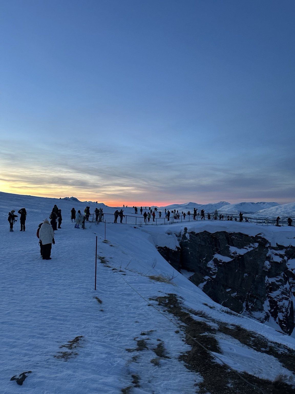 People on a snowy ridge at sunset
