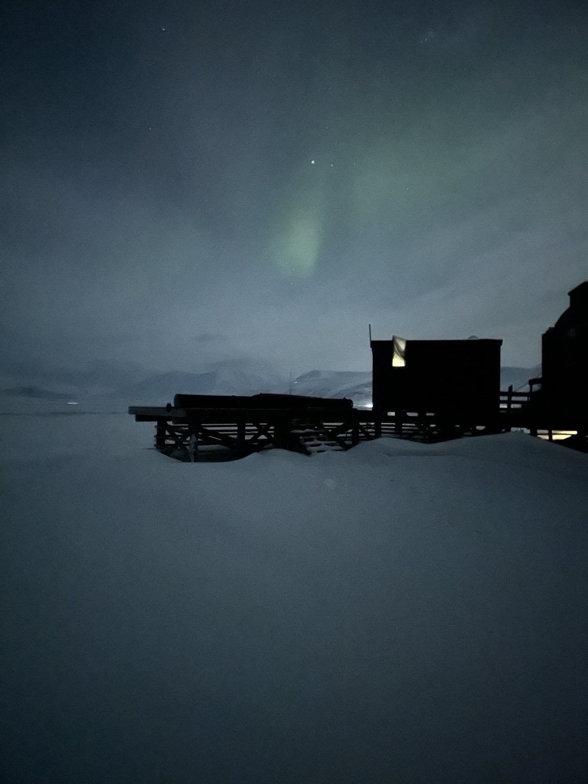Faint northern lights over a snowy settlement