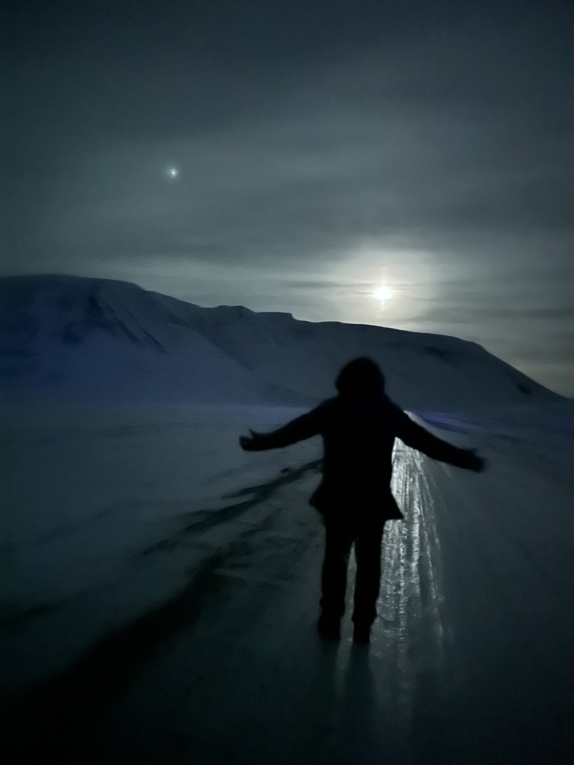 Traveler standing on a snow-covered road beneath a mountain