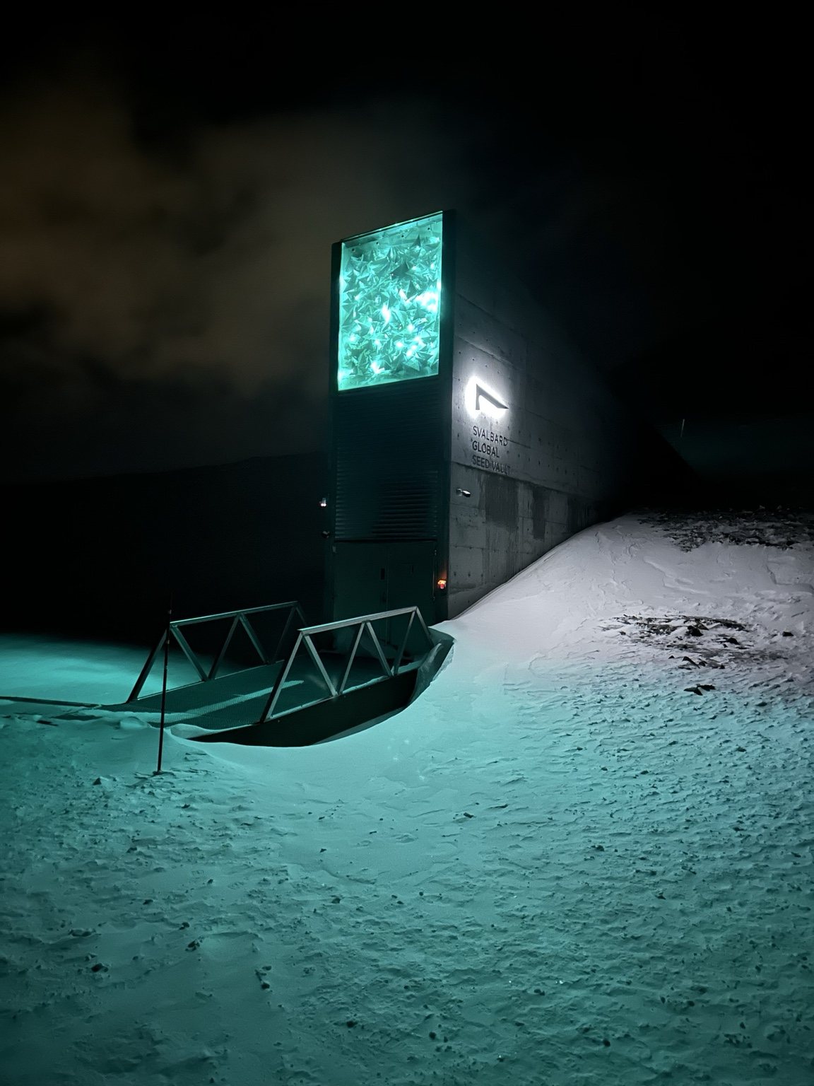 Lit building and sled in deep snow at night